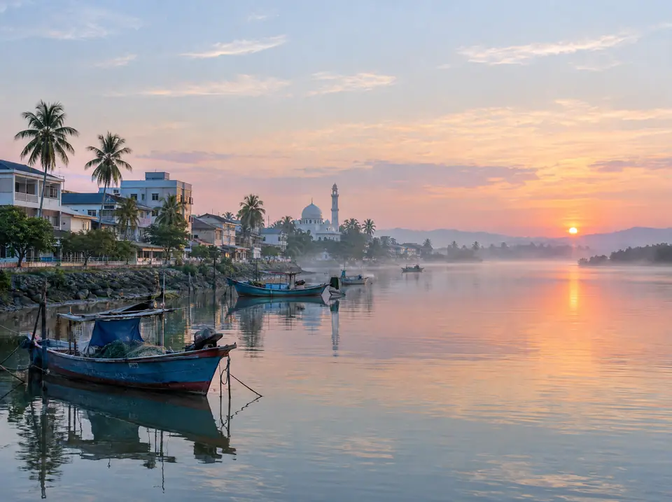 Calm river mouth in an east coast town at dawn, with fishing boats and a mosque dome in the distance